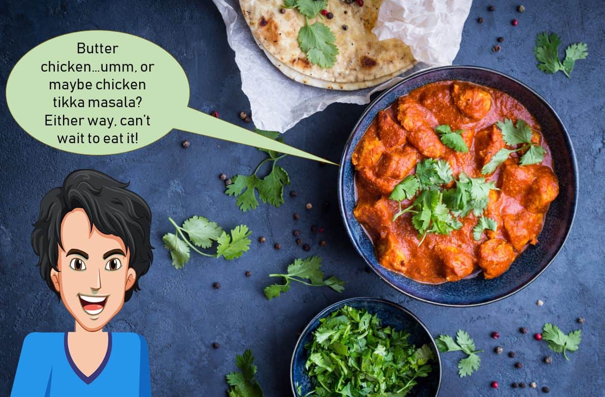 chicken tikka masala in large bowl next to fresh herbs and naan bread