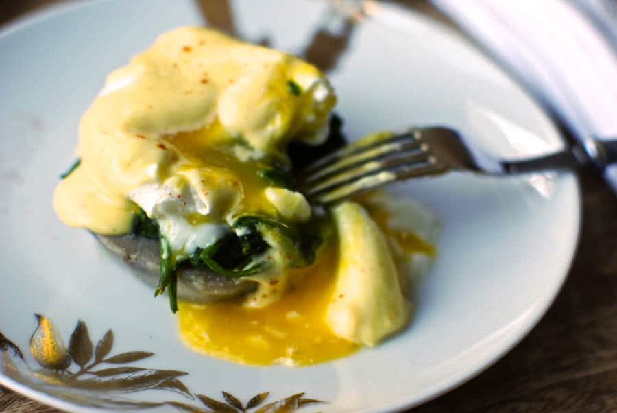 sliced eggs sardou on a white plate covered with egg yolk