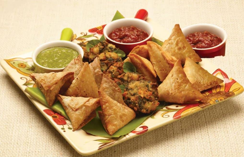 plate of samosas with dipping sauces