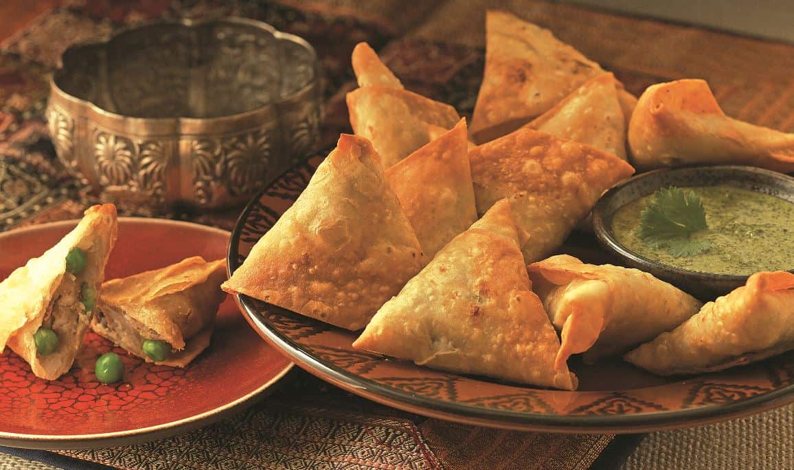 indian samosas on two plates with dipping sauce