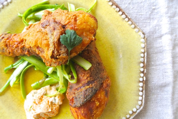 indian fried chicken drumsticks on a yellow plate with dipping sauce