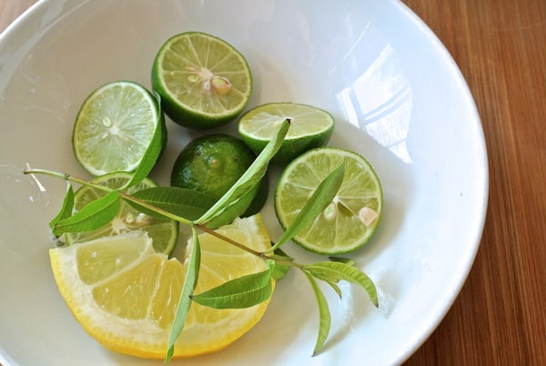 lemon slice, halved limes, and lemon verbena leave in white bowl