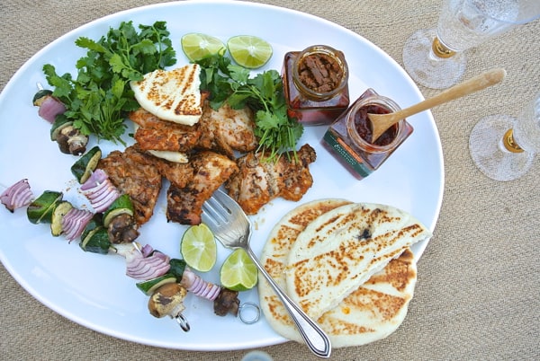 grilled tandori chicken on a plate with naan, veggie skewers, and chutney