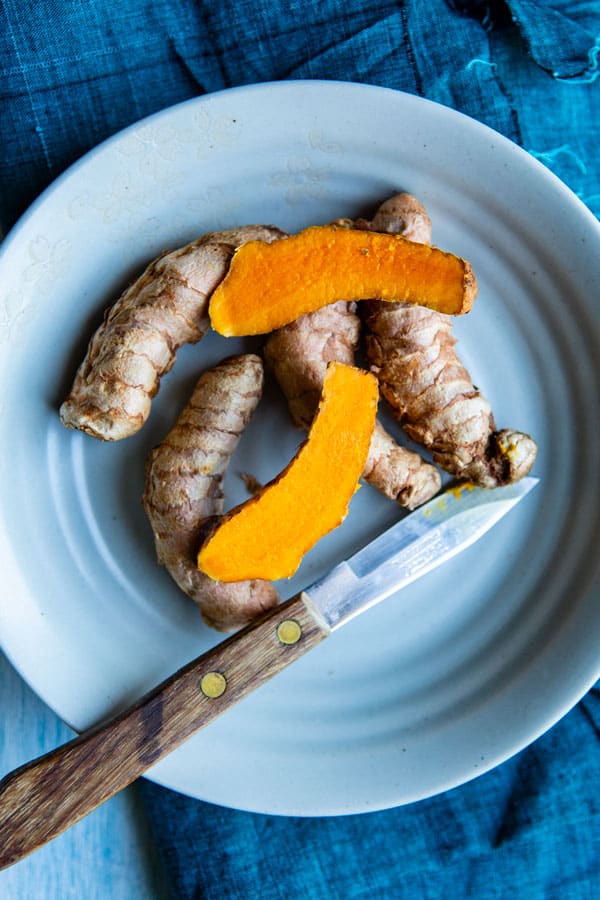 Fresh Turmeric root in a plate, cut in half for making turmeric golden milk