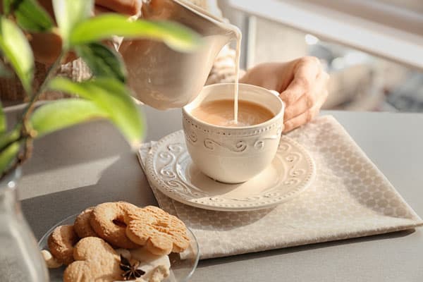 A person pouring chai into a tea cup