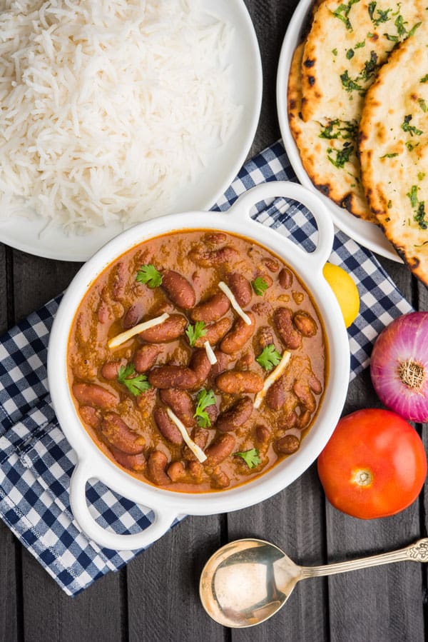 Rajma Masala, rice, naan and some salad served on a table.