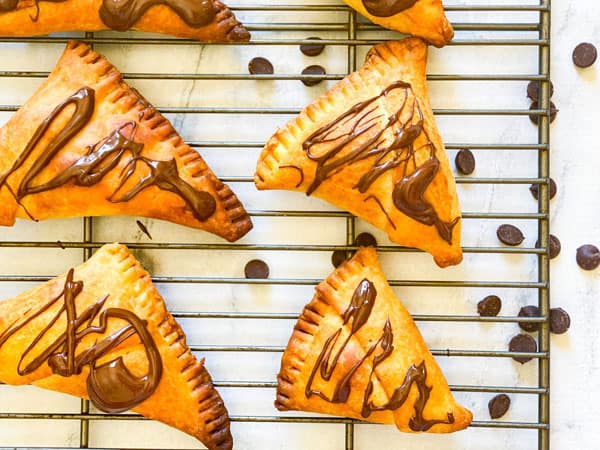 chocolate samosa laid out on a cooling rach with chocolate chips sprinkled around