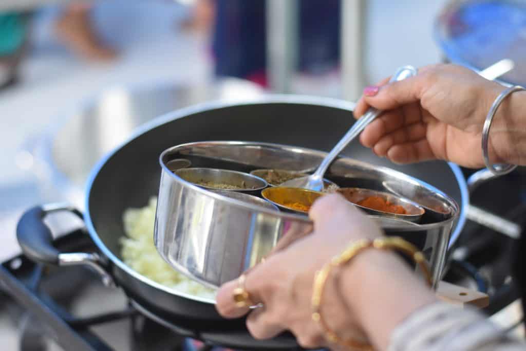 Image of a person spooning from a masala dabba